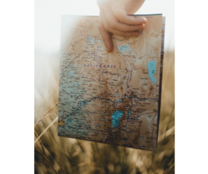 map in hand, in a field -enjoy the journey