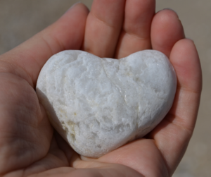 heart shaped rock in hand- giving